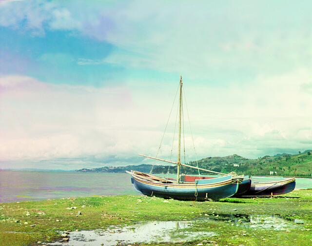 a trichromy by Prokudin-Gorsky showing two boats out of the water, on a lake shore.